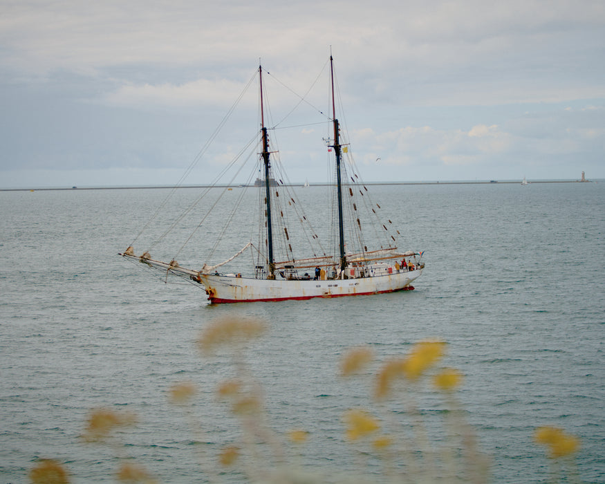Sailboat at sea, coming to port, with a cloudy sky