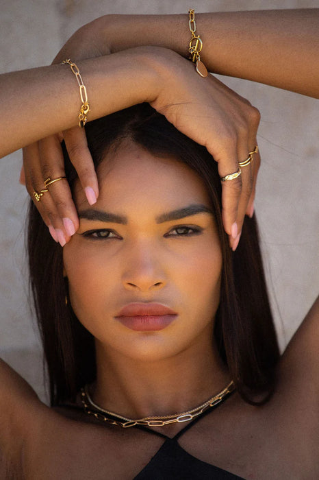 Woman wearing gold jewellery with a neutral background
