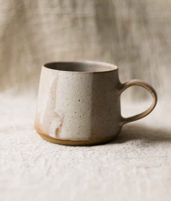 Beige ceramic mug on a textured surface with a neutral linen background