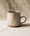 Beige ceramic mug on a textured surface with a neutral linen background