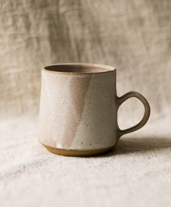 Beige ceramic mug on a textured surface with a neutral linen background