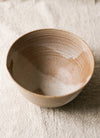 Beige ceramic bowl on a textured beige linen surface