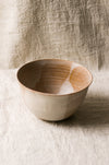 Beige ceramic bowl on a textured beige linen surface