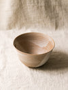 Beige ceramic bowl on a textured beige linen surface