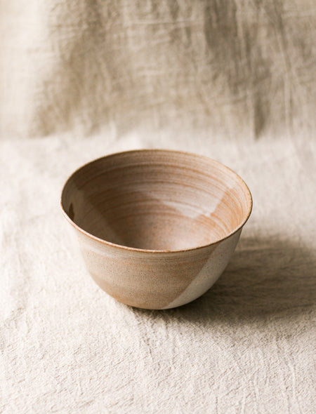 Beige ceramic bowl on a textured beige linen surface