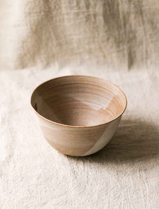 Beige ceramic bowl on a textured beige linen surface