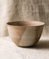 beige ceramic bowl with a speckled pattern on a neutral linen background