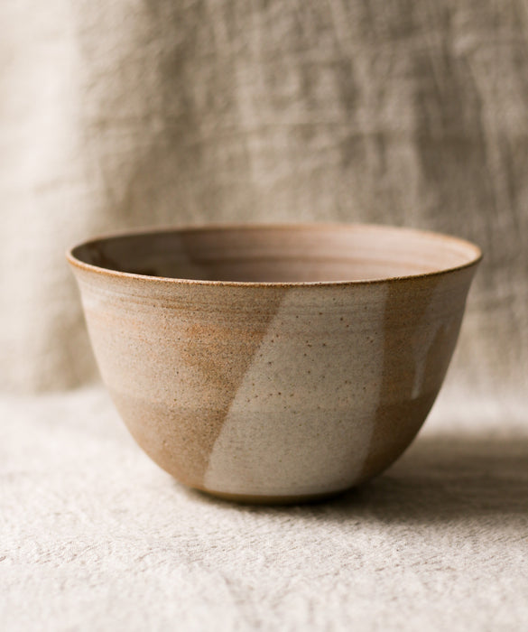 beige ceramic bowl with a speckled pattern on a neutral linen background