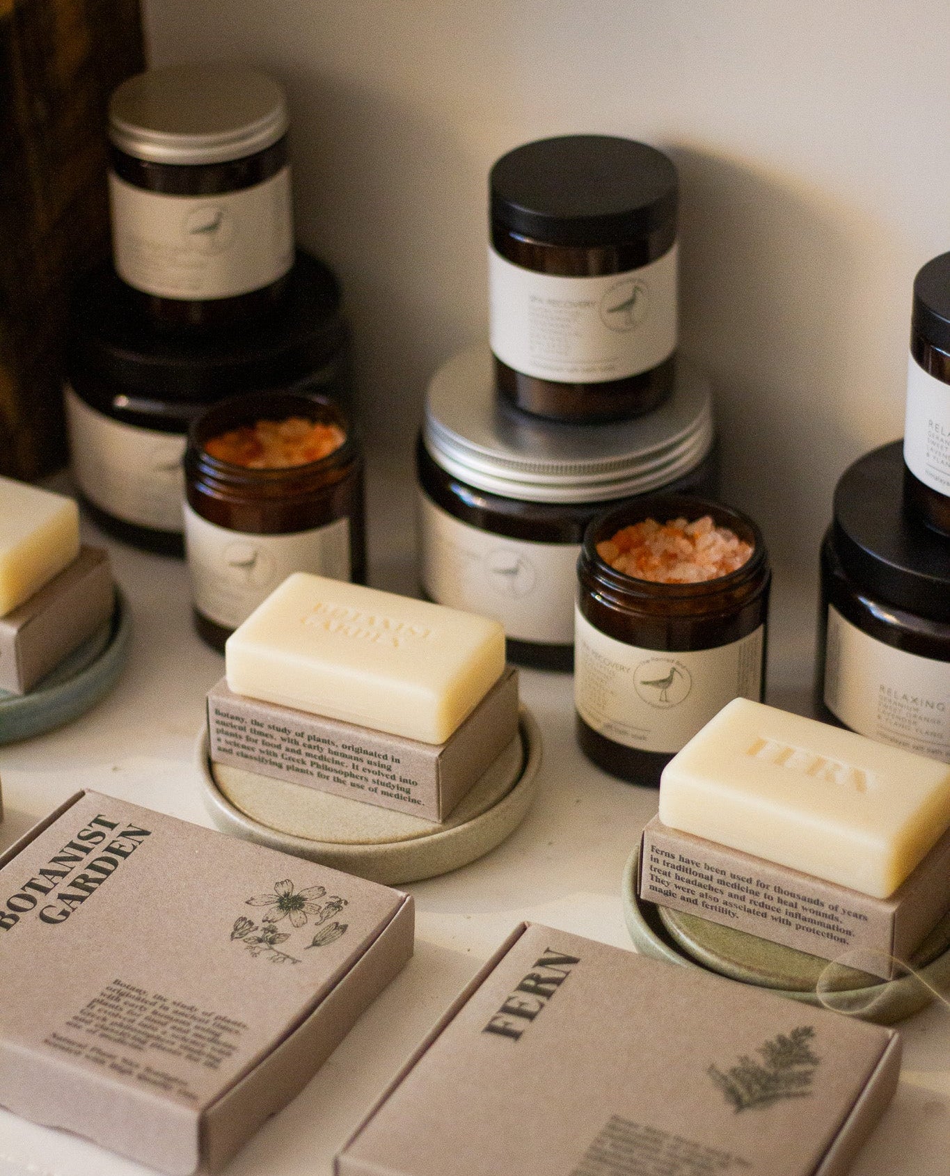 Collection of skincare products including jars, bottles, and soaps on a neutral background