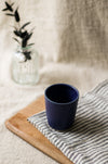 Navy blue mug on a striped cloth with a blurred background