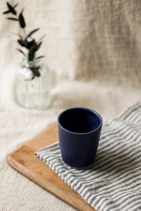 Navy blue mug on a striped cloth with a blurred background