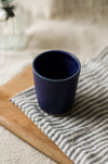Navy blue ceramic cup on a striped cloth with a blurred background