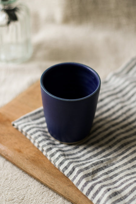 Navy blue ceramic cup on a striped cloth with a blurred background