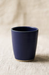 Navy blue ceramic cup on a beige surface