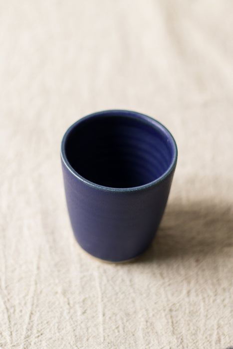 Blue ceramic cup on a beige surface