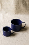 Two blue mugs on a beige textured surface