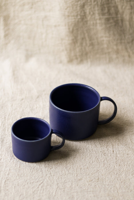 Two blue mugs on a beige textured surface