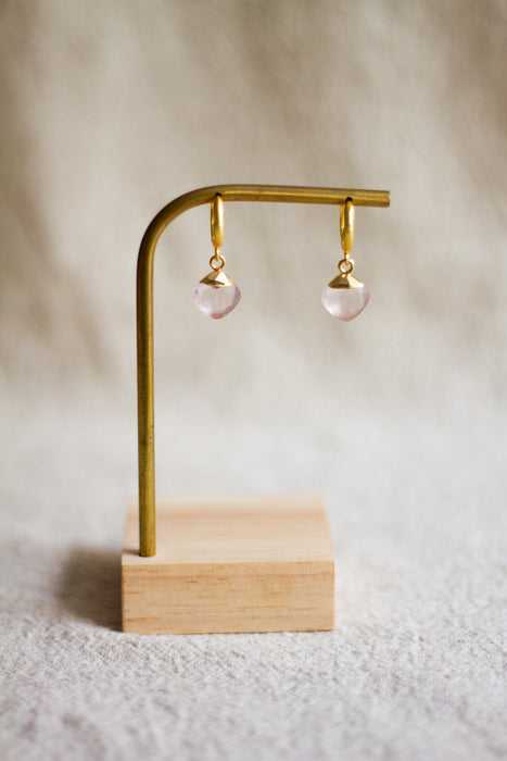 brass earring stand with rose quartz  earrings on a beige background