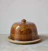 Brown ceramic butter dish on a light grey surface with a grey background