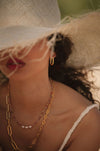 model wearing a straw hat and gold jewellery with a blurred background
