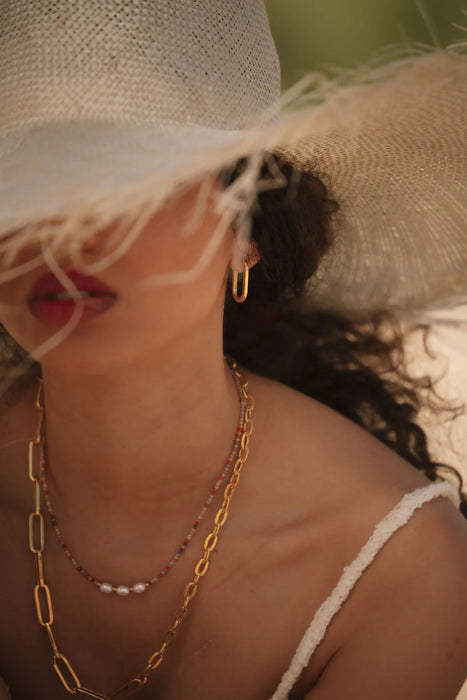 model wearing a straw hat and gold jewellery with a blurred background