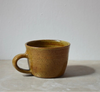 Brown ceramic mug on a light grey surface with a plain background