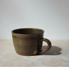 dark green ceramic mug on a light surface with a grey background