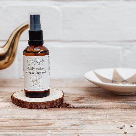 Bottle of moksa cleansing oil on a wooden surface with a neutral background