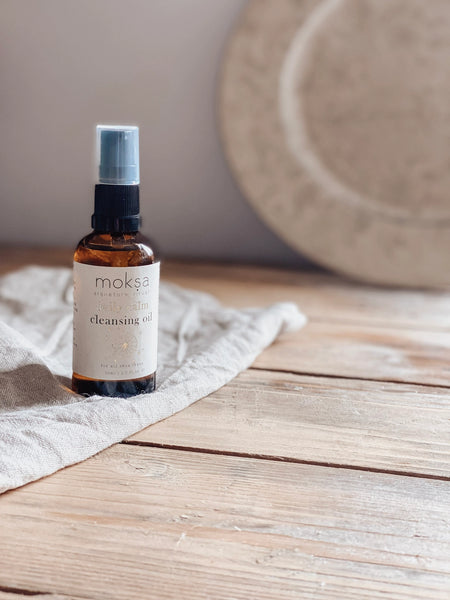 Bottle of moksa cleansing oil on a wooden surface with a neutral background