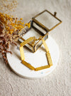 Gold textured bracelet on a white coaster with dried flowers on a beige linen surface