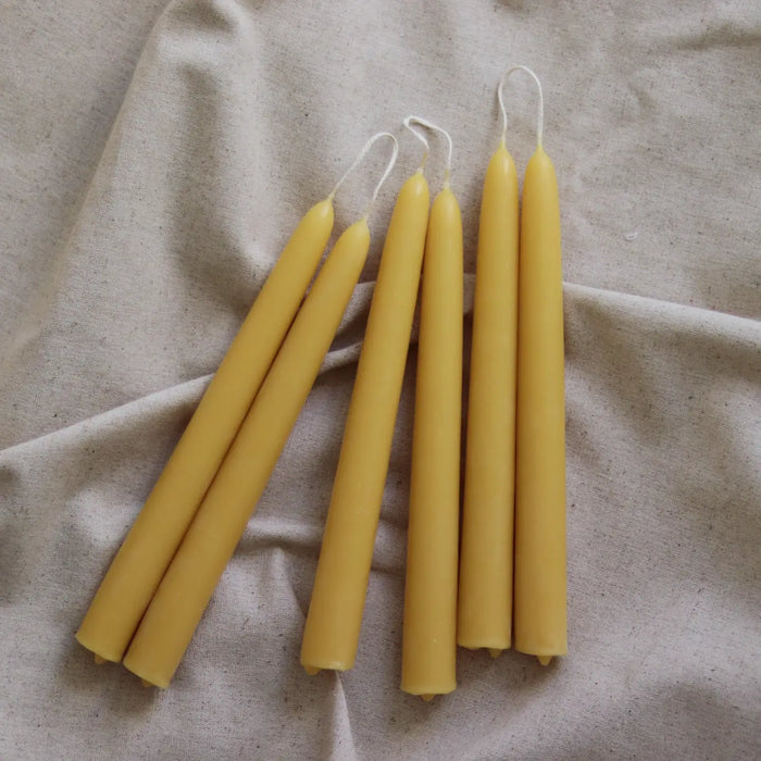 Five beeswax candles on a beige fabric background