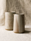 2 beige speckled ceramic pitchers with a textured surface on a neutral background