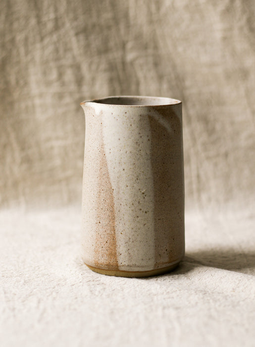 Beige Speckled ceramic pitcher with a textured surface on a neutral background