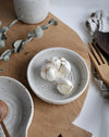 White ceramic garlic dish with garlic cloves on a wooden chopping board with wooden utensils 
