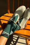 Sage shoes with green socks on a wooden chair