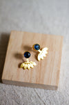 Gold stud earrings with iolite stones on a wooden block