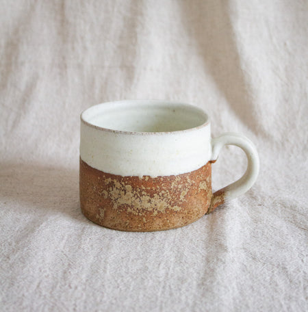 Cream and stoneware mug against a neutral linen backdrop