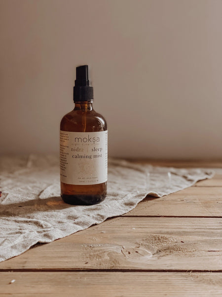 Bottle of moka natural sleep calming mist on a wooden surface with a beige background