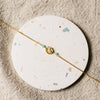 Gold bracelet with gemstone beads on a round, speckled coaster