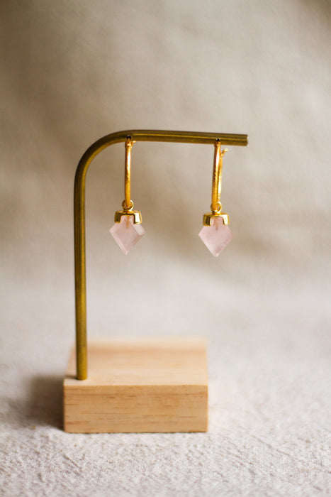 Gold hoop earrings with rose quartz stones on a beige background