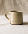 Beige ceramic mug on a textured surface with a neutral background