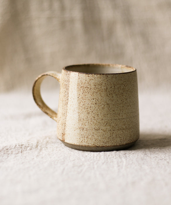 Beige ceramic mug on a textured surface with a neutral background
