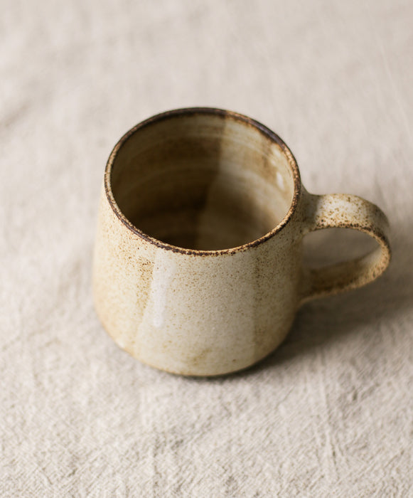 Ceramic beige mug with a textured surface on a beige background