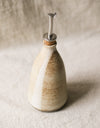 Ceramic oil bottle with a cork lid on a beige background