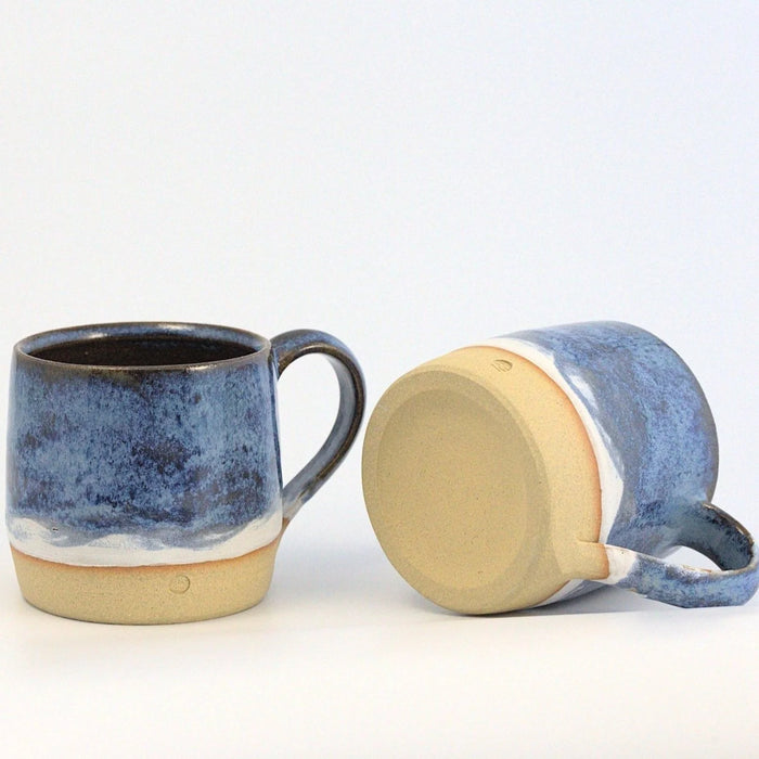 Two ceramic mugs with blue and beige design on a white background