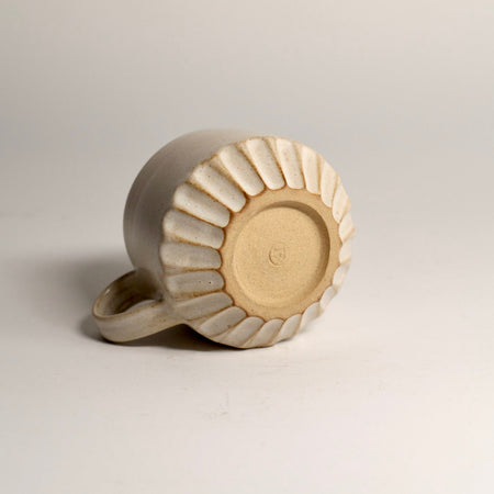 Ceramic mug with carved design on a light grey background