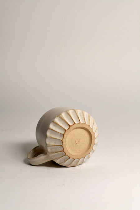 Ceramic mug with carved design on a light grey background