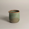 Green ceramic jug on a light grey background