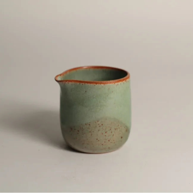 Green ceramic jug on a light grey background
