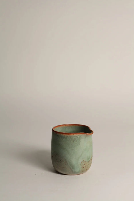 Green ceramic jug on a light grey background